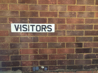 Parking visitors signs on red brick wall
