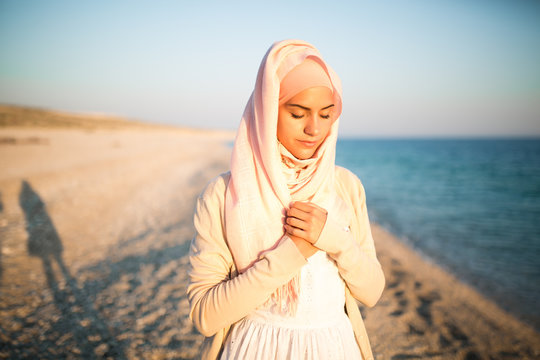 Muslim woman on the beach spiritual portrait.Humble muslim woman praying on the beach.Summer holiday,muslim woman walking on the beach