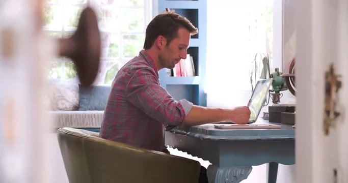Man Sitting At Desk Working In Home Office