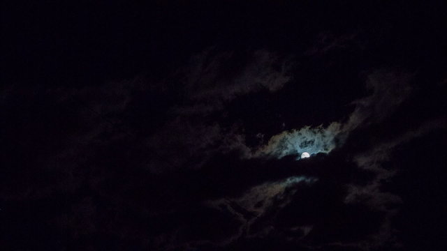 Shiny moon at night behind clouds