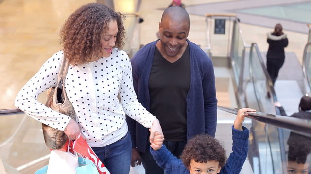 Child On Trip To Shopping Mall With Parents On Escalator