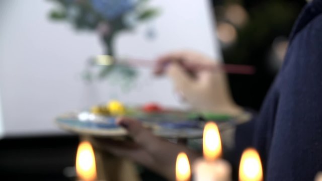 Refocus from candles to artist drawing on canvas