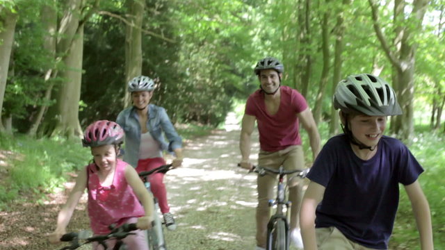Family Riding Mountain Bikes Along Track