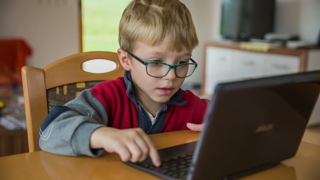 Boy with glasses working on laptop computer