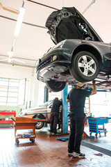 Motor mechanic working on a car on a hoist