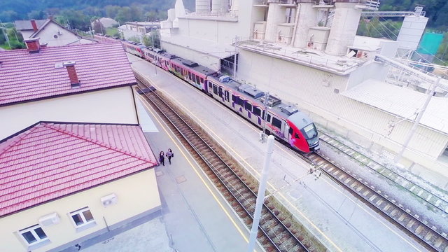 Passenger train leaving station aerial panning