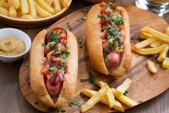 hot dogs with tomato salsa and onions on wooden board, top view