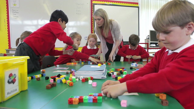 Pupils And Teacher Working With Coloured Blocks