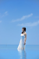 海辺に立つワンピースの若い女性