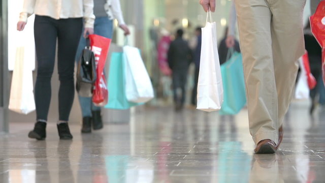 Close Up Of Shopper's Feet Carrying Bags In Shopping Mall