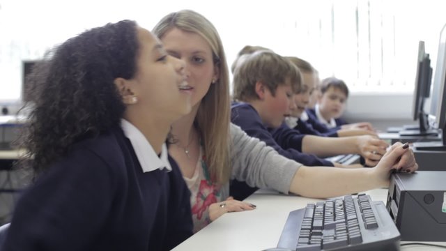 Teacher Helping Female Pupil In Computer Class