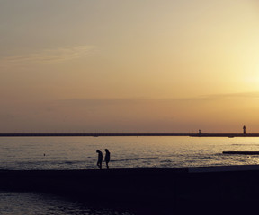Fototapeta na wymiar Couple walking at the beach in the evening