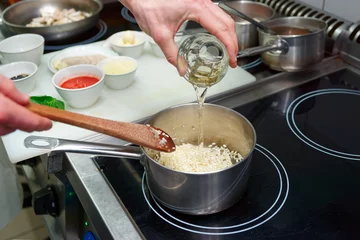 Crédence de cuisine en verre imprimé Cuisinier Chef is adding white wine to risotto