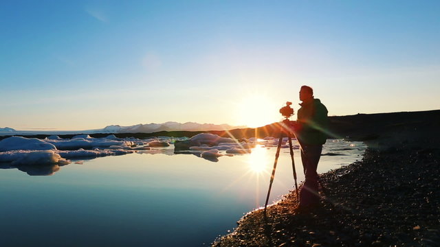A photographer takes photo of icebergs in Glacier Lagoon at Sunrise. Jokulsarlon estuary
