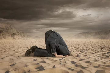 Fotobehang Jonge zakenman die zijn hoofd in het zand verbergt © rangizzz