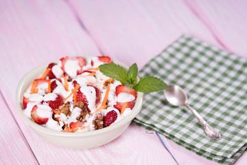 Yogurt with strawberries, carrots, walnuts. Pink background.