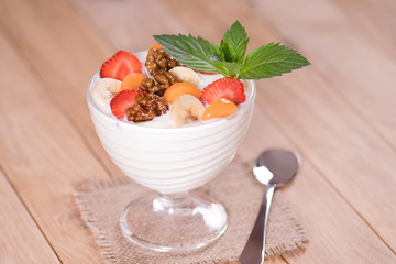 Yogurt with strawberries and banana carrot and walnuts on a wooden table