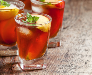 Peach Tea with pieces of fruit and mint on a wooden background,