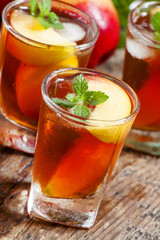 Peach Tea with pieces of fruit and mint on a wooden background,