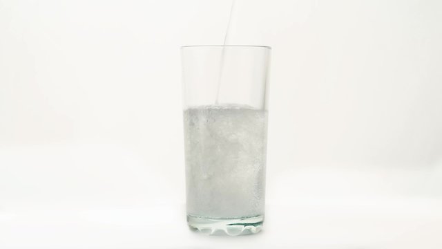 Carbonated water is poured into a glass on a white background