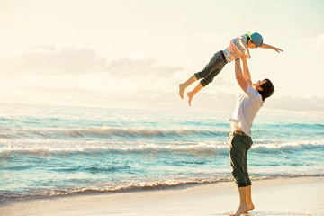 Father and son having fun together in sunset ocean on summer