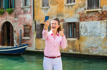 Fototapeta na wymiar Woman tourist in Venice taking selfie and giving thumbs up