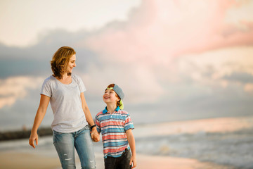 Young happy beautiful mother and her son having fun on the beach