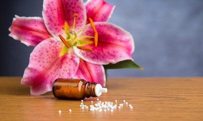 homeopathic globules on wooden ground with lilly