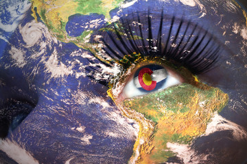 womans face with planet Earth texture and colorado state flag inside the eye.
