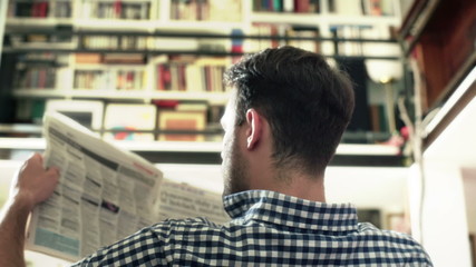Man sitting back and reading newspaper downstairs
