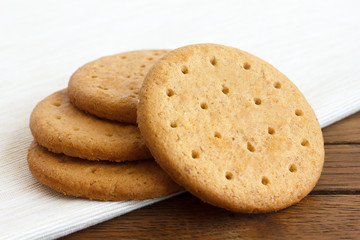 Stack of sweetmeal digestive biscuits on dark wood and napkin.