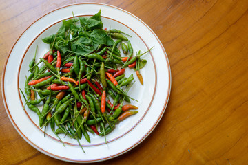 Green, red chili peppers on white dish