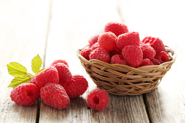 Red raspberry in basket on a grey wooden background