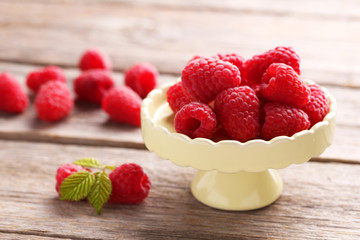 Red raspberries on cake stand on grey wooden background