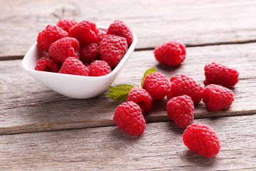 Red raspberries in bowl on grey wooden background