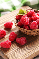 Red raspberries on cutting board on grey wooden background