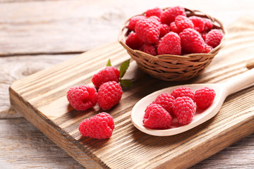 Red raspberries on cutting board on grey wooden background