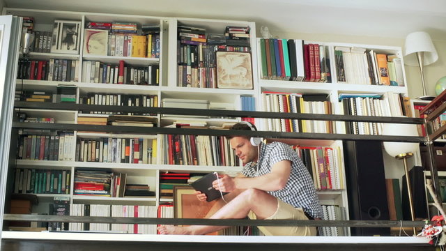 Man sitting on entresol and listening music on tablet

