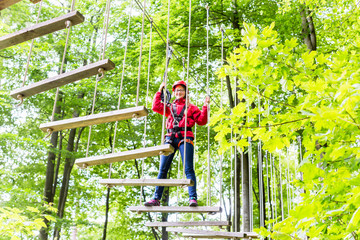 Kind passiert Hängebrücke im Klettergarten