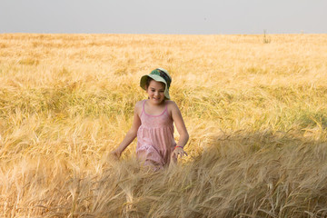 Naklejka na ściany i meble Happy little girl playing in the wheat