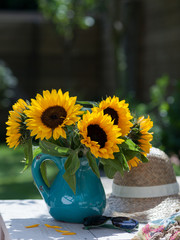 Sunflowers in ceramic vase in a garden with hat and sunglasses 