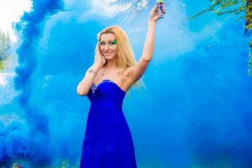 Obraz na płótnie Canvas Beautiful young woman in a cloud of a bright blue smoke
