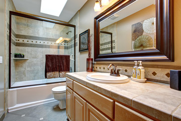 Elegant bathroom with glass shower and large framed mirror.