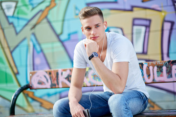 Male teenager with smartphone and earphones in urban city