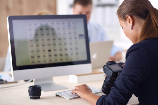 Female photographer sitting on the desk with laptop