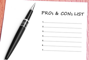 Pen  and notes paper with pros & cons list