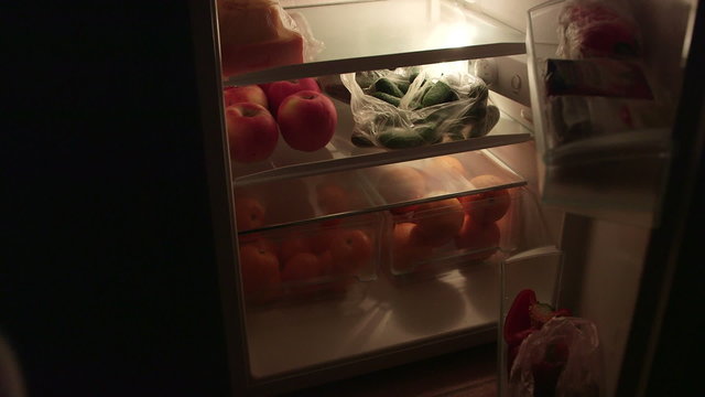 Man takes out food from the fridge at night