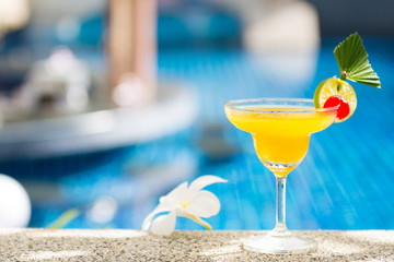 yellow cocktail with lime by the pool