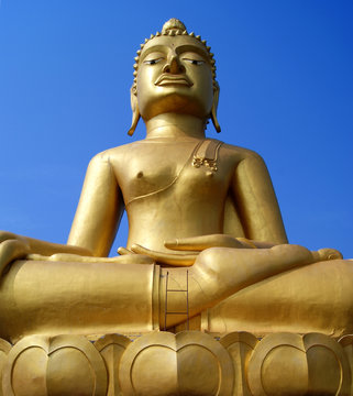 Huge golden Buddha Statue is under blue sky.