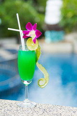 green cocktail with lime by the pool